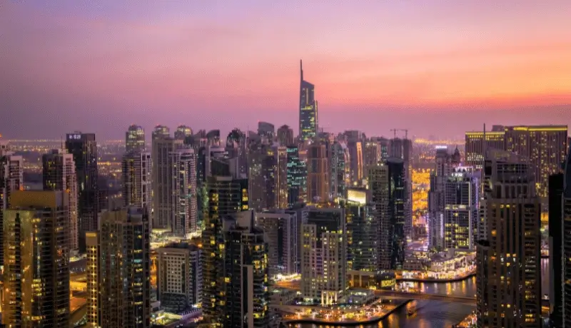 Dubai City skyline at sunset with tall buildings and glowing lights
