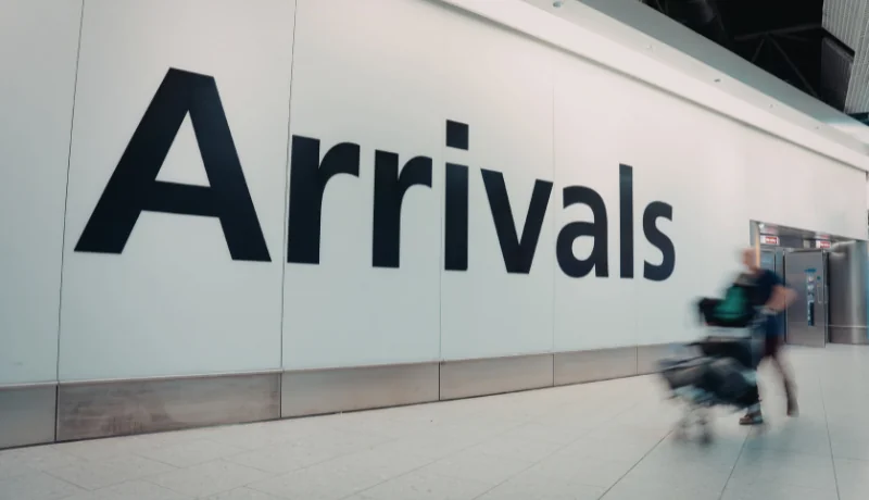 Person walking with luggage in an airport arrivals area